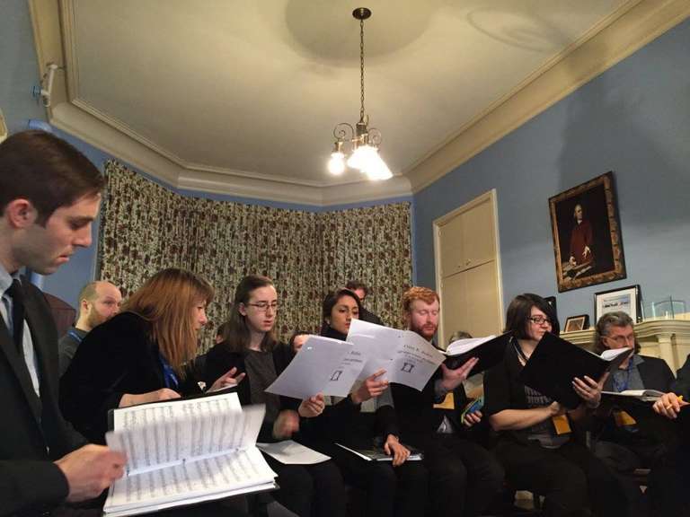 In a blue-walled practice room, Jamie practices a piece with other members of C4, who are holding sheet music.