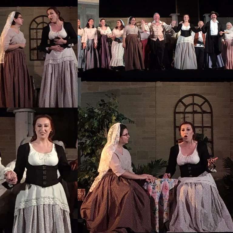 Jamie on stage with other singer/actors during an opera. She wears a peasant costume and a veil behind her head.