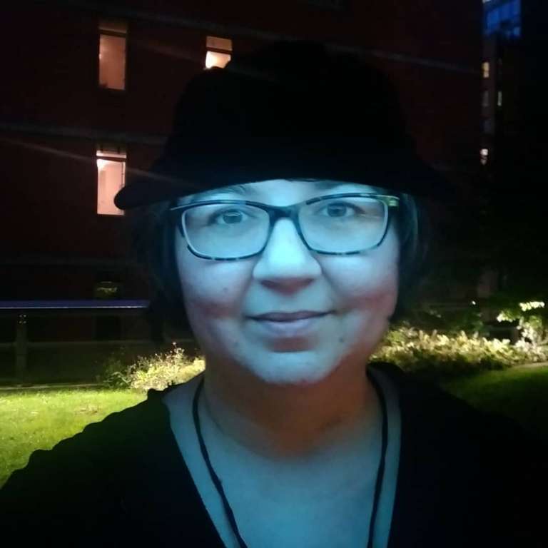 Jamie performing at the Mile Long Opera on the High Line in Manhattan, at night. She is illuminated by a blue light.