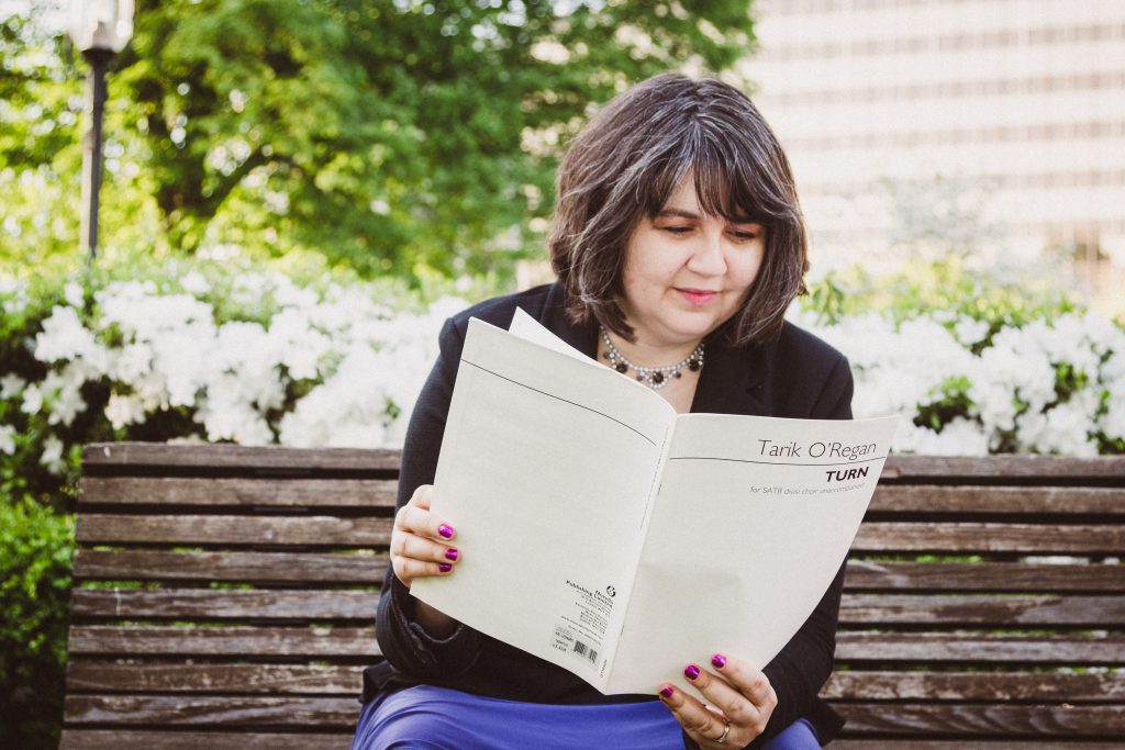 Jamie Klenetsky Fay sits on a bench, reading over a score